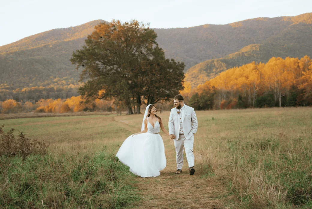 Bride and groom posing on a sunny day in the Great Smoky Mountains with a scenic mountain views and fall foliage on the background