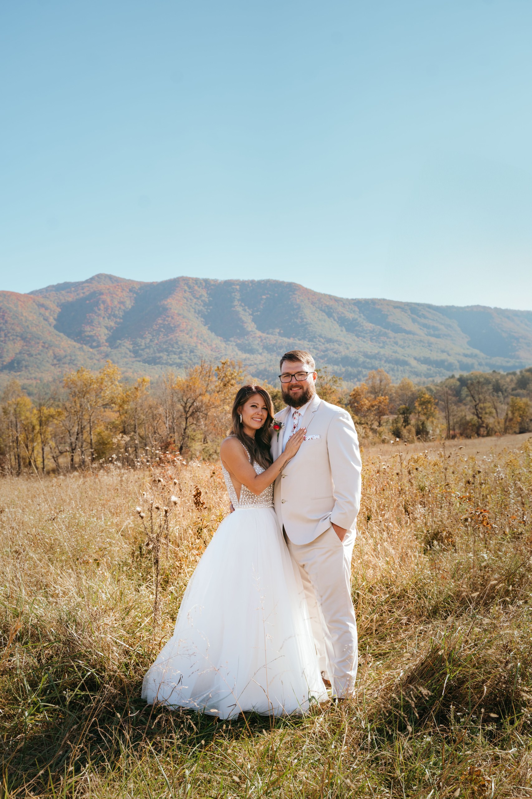 Bride and groom posing on a sunny day in the Great Smoky Mountains with a scenic mountain views and fall foliage on the background