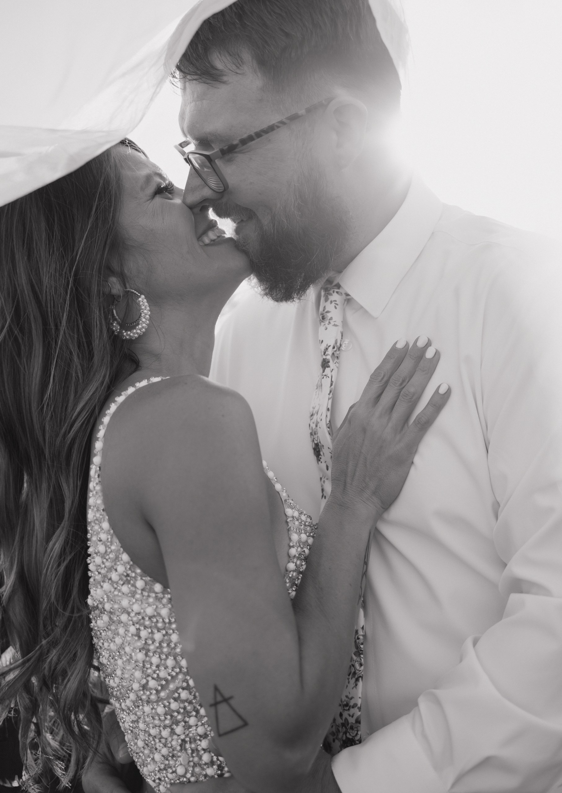 Joyful bride and groom sharing an intimate moment captured in soft sunlight