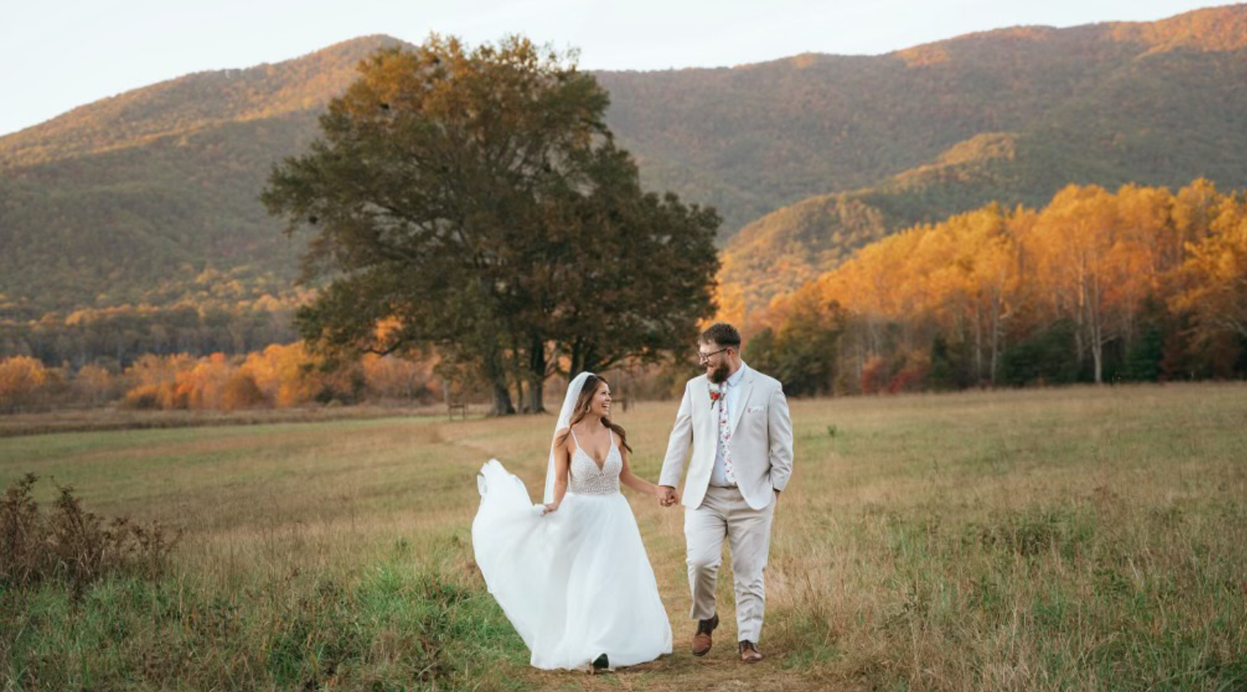 Bride and groom posing on a sunny day in the Great Smoky Mountains with a scenic mountain views and fall foliage on the background