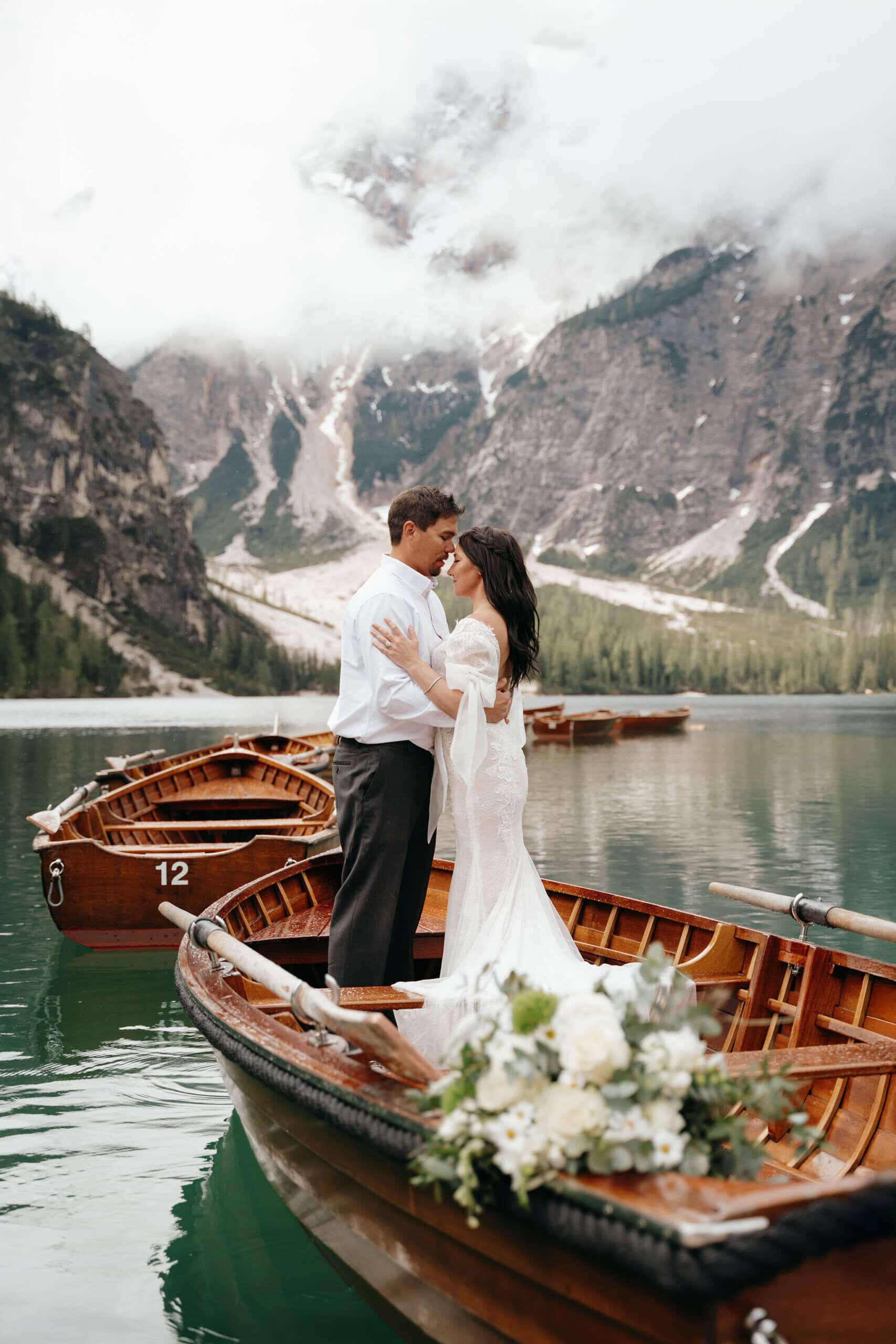 Couple embracing on a wooden boat in the Dolomites during a romantic mountain elopement