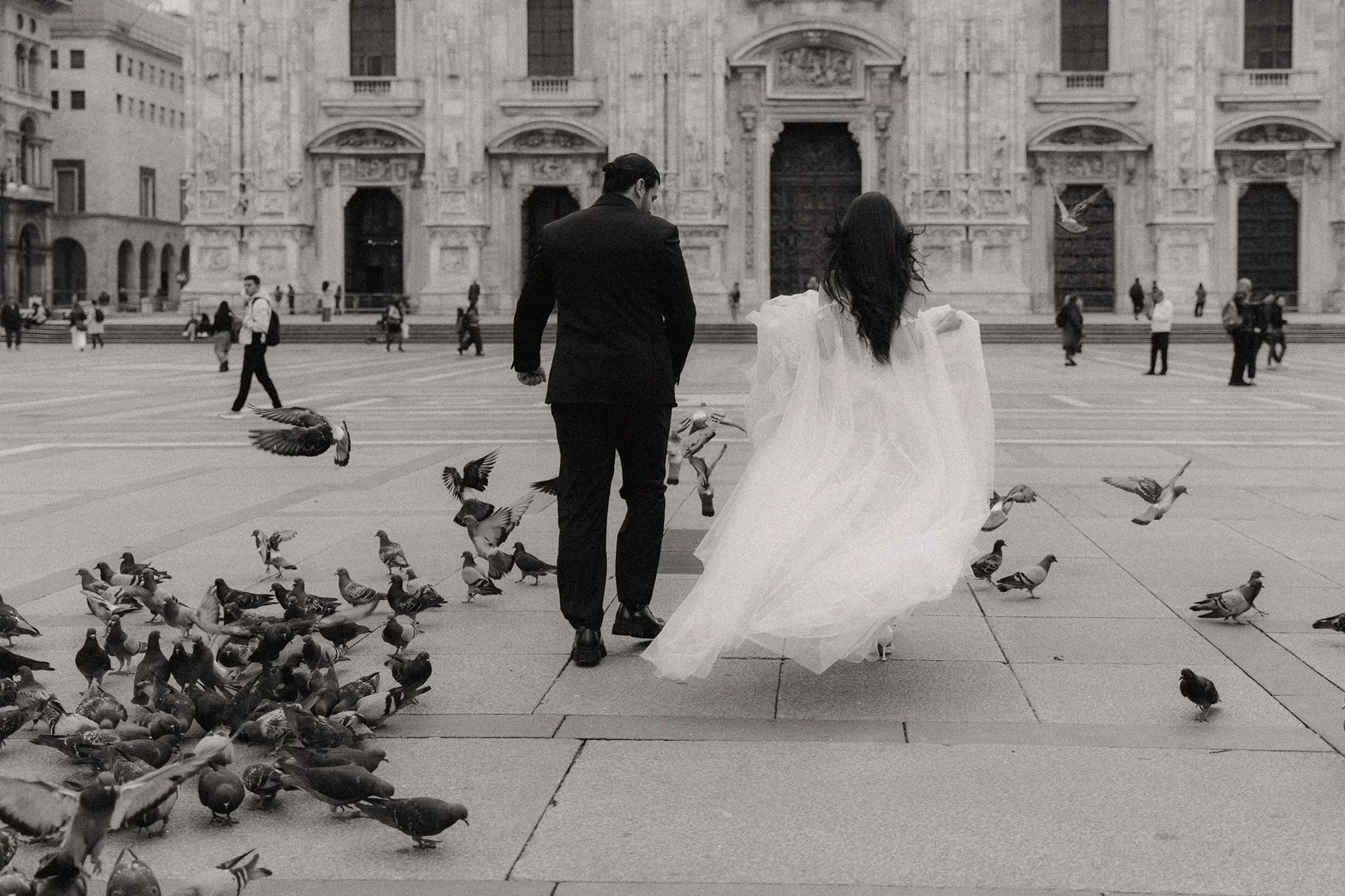 Couple eloping in Milan walking together near the Duomo with pigeons in the foreground