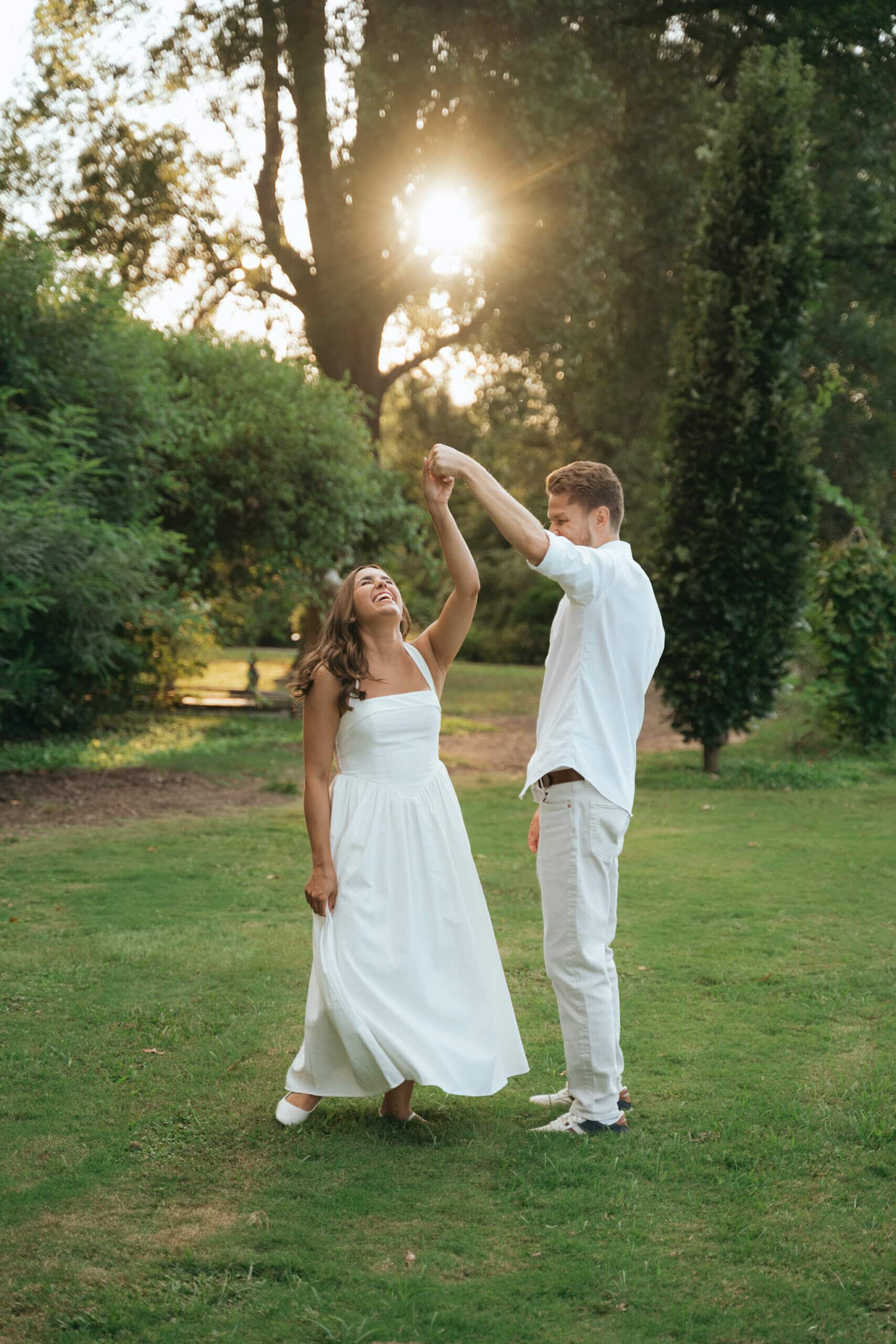 Engaged couple dancing under trees during an outdoor engagement session