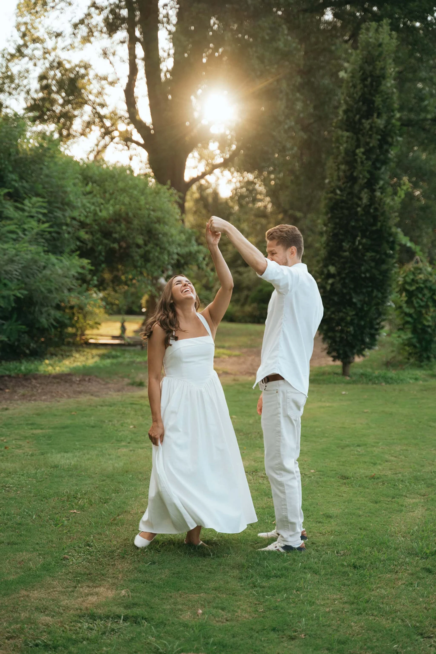 Engaged couple dancing under trees during an outdoor engagement session